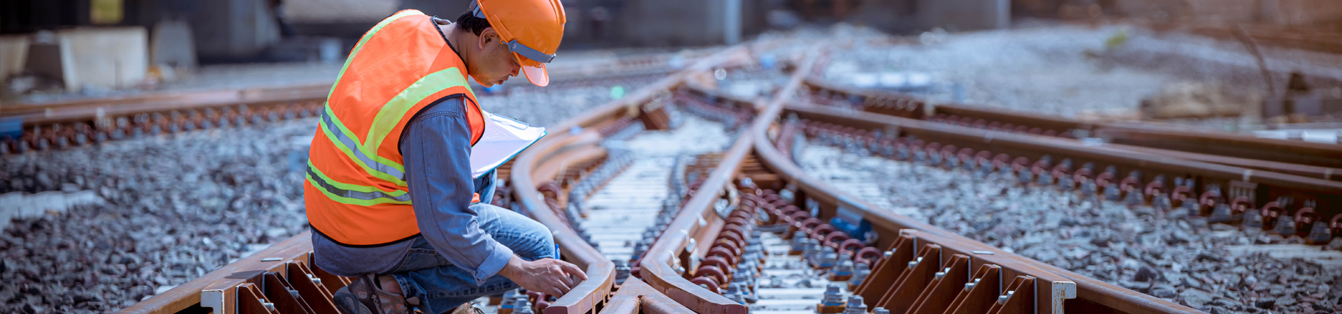 Image of a man in high-visibility gear inspecting railroad