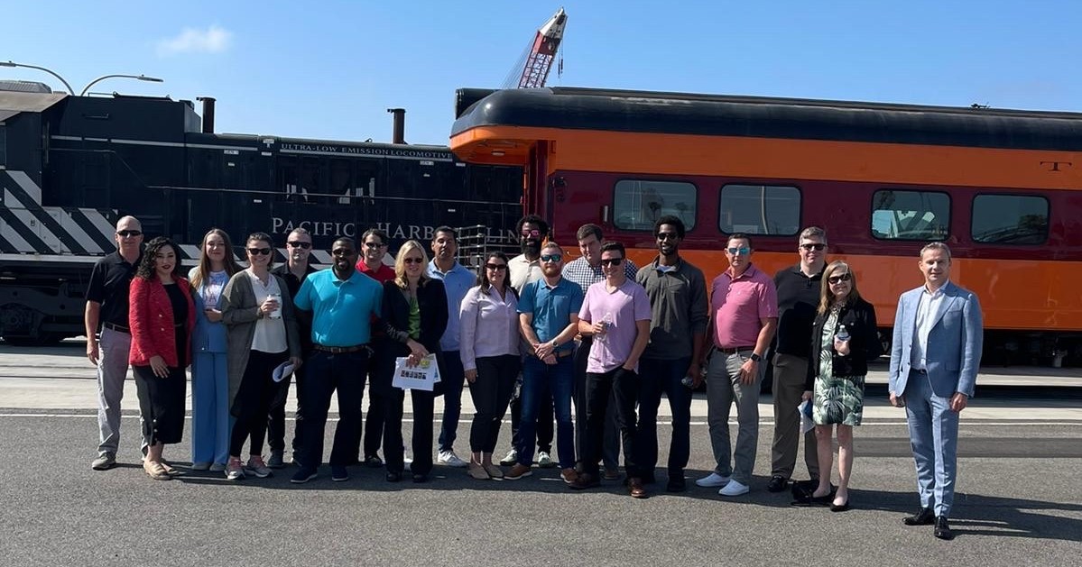 University of Denver graduate students stand in front of a Pacific Harbor Line locomotive